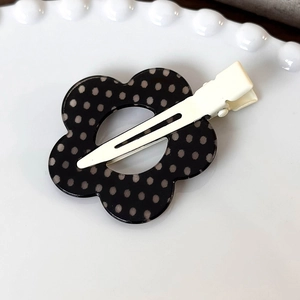 Primo piano del fermaglio per capelli a fiore a pois bianchi e neri su piatto decorativo