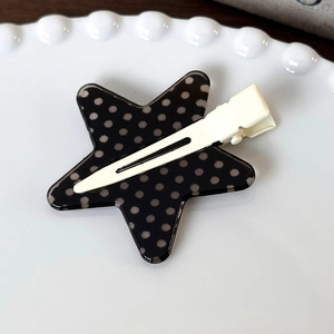 Dettaglio di un fermaglio per capelli a forma di stella a pois su piatto di ceramica