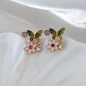 Macro shot of gold butterfly and flower earrings with enamel petals and colorful zircons
