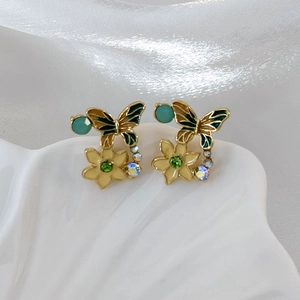 Macro shot of butterfly enamel earrings with floral details on shell porcelain plate