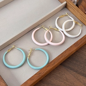 Three pairs of colorful hoop earrings in pastel blue, pink and white with golden clasps