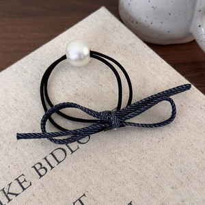 Détail de l'élastique à cheveux avec nœud en jean bleu et perle sur doubles liens noirs