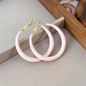Detailed close-up of light pink round hoop earrings with elegant golden french clasps