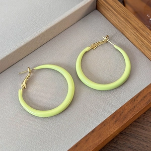 Detail of light green enamel hoop earrings with gold plating on a velvet tray