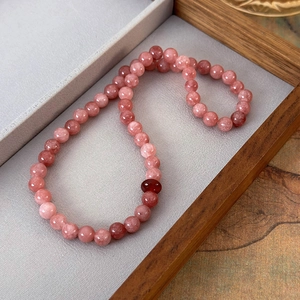 Detail of pink strawberry quartz beaded bracelet on a classic walnut wood tray