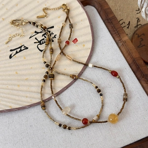 Ethnic beaded necklace with natural stones and golden tube beads on a calligraphy fan