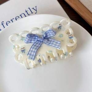 Dettaglio del fermaglio per capelli con orsetto, fiocco blu e cuori intagliati