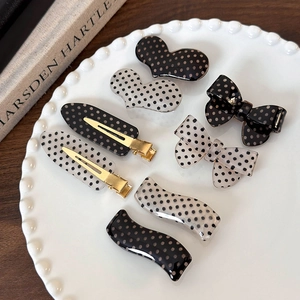 Close-up of assorted polka dot hair clips including bow and heart shapes on a decorative plate