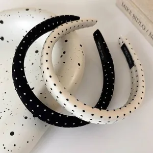 Handmade black and white polka dot satin headbands displayed on a decorative ceramic tray