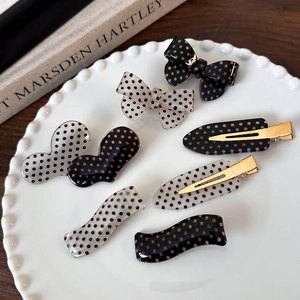 Polka dot bow hair clips set with heart and wavy shapes on a decorative plate