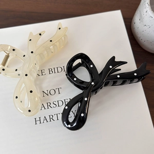 Elegant polka dot bow hair claws in black and white styles on a minimalist card background