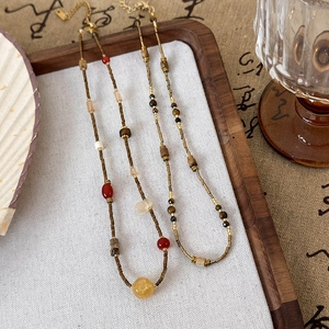 Macro view of beaded necklaces with natural stones and gold steel clasps in a wooden tray