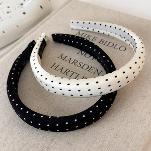 Detail view of retro polka dot satin headbands in black and white on a book