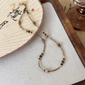 Detailed view of beaded necklace with tiger eye stones and gold accents on a zen plate
