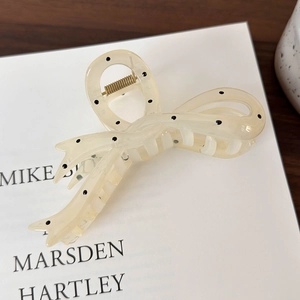 Close-up of cream bow hair claw with black polka dots on a vintage book prop
