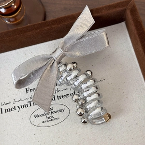 Detailed macro view of a silver satin bow hair claw with elegant metallic beads inside