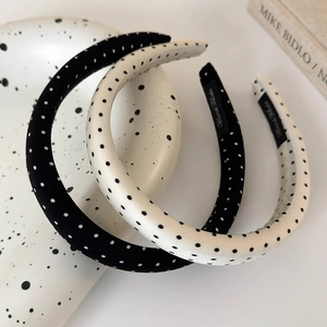 Detailed view of handmade polka dot satin headbands on a textured white ceramic plate
