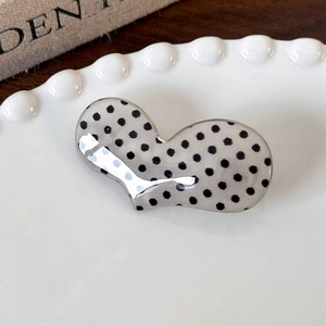Close-up of polka dot acrylic hair clip with silver metallic inlay on a ceramic tray