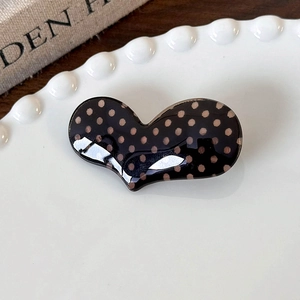 Close-up of heart-shaped hair clip with polka dot pattern on a ceramic plate