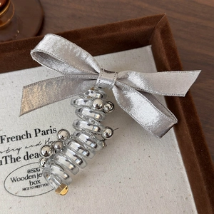 Close-up of silver satin bow hair tie with transparent spiral cord and metallic beads
