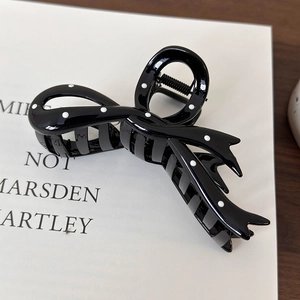 Detailed view of the black bow hair claw clip with classic white polka dot pattern