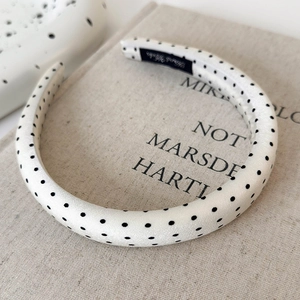 Detailed view of the padded satin headband featuring black polka dots on cream fabric
