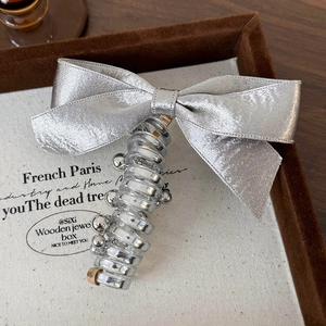 Detailed view of silver satin bow hair tie with spiral pendants in a vintage display box