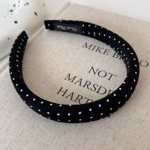 Top view of a vintage black satin headband with white polka dots on linen background