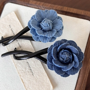 Détail de pinces à cheveux fleur camélia en denim bleu avec bords effilochés