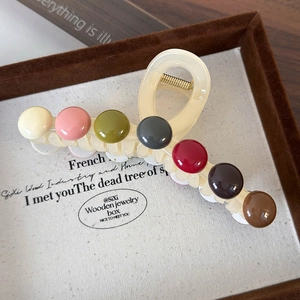 Détail d'une pince à cheveux crème ornée de sept perles colorées et polies