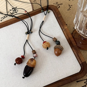 Détail d'un collier pendentif pignon de pin artisanal avec perles en céramique