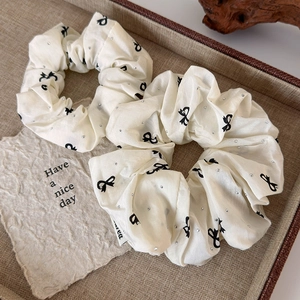 Creamy fabric hair scrunchies set with black bow prints and tiny rhinestones for women