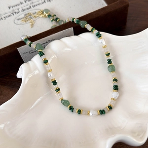 Macro detail of peacock green beads and pearls on a white shell decorative tray