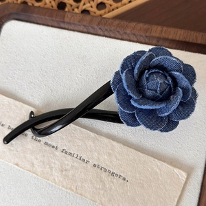 Détail d'une fleur rose en denim bleu sur une pince à cheveux élégante en résine noire