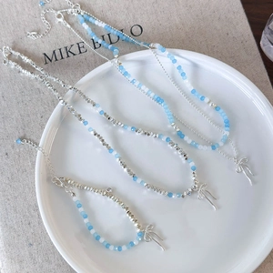 Detail of light blue and white beads necklace with silver bow pendant on a plate