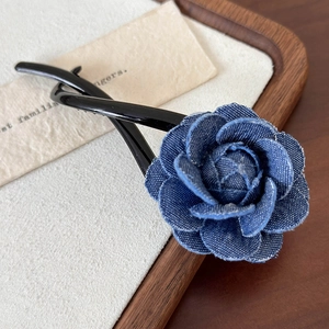 Détail macro d'une rose en jean bleu et d'une pince à cheveux torsadée sur rembourrage