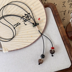 Détail du collier artisanal en perles de pignon sur un éventail chinois pliant