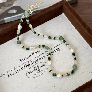 Detail of beaded necklace with malachite, baroque pearls and gold clasp on canvas