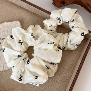 Detail of cream ballet core hair scrunchies with black bows and sparkling rhinestones