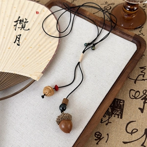 Détail d'un collier ethnique fait main avec pendentif gland et perles en bois sur plateau