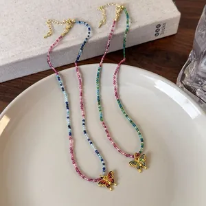 Détail de colliers papillon perlés colorés exposés sur une assiette décorative en céramique