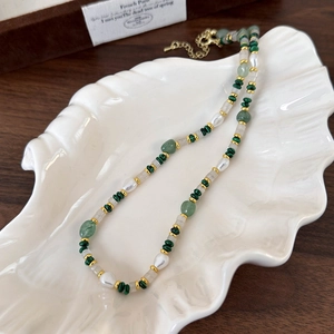 Detail of beaded necklace with malachite, pearls and gold lobster clasp on shell tray