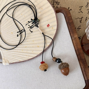 Détail du pendentif rétro avec gland et coque de noix sur une cordelette tressée