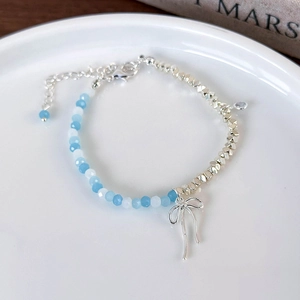 Detail of beaded bracelet with blue crystals, silver metal beads and bow pendant