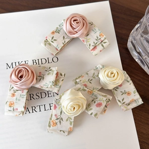 Detail of silk rose and floral bow hair clips in light pink and cream colors