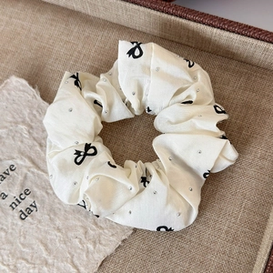 Detail of white satin scrunchie with black bow prints and sparkling rhinestones