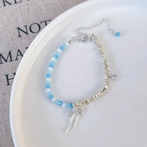 Detailed shot of a beaded necklace featuring blue pearls and a silver bow pendant