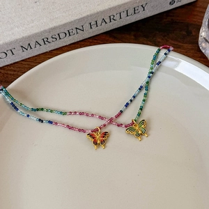 Détail de pendentifs papillon en émail avec perles colorées sur une assiette en céramique