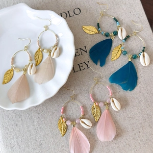 Bohemian feather earrings set with shell accents and beads on rustic fabric background