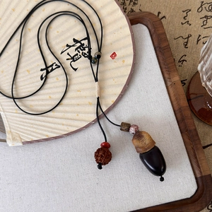 Détail du pendentif pignon poli et graine de bodhi sur collier en cordon